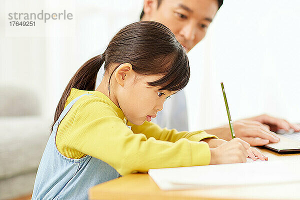 Japanisches Kind lernt zu Hause mit seinen Eltern