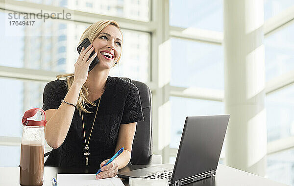 Lächelnde Geschäftsfrau telefoniert im Büro