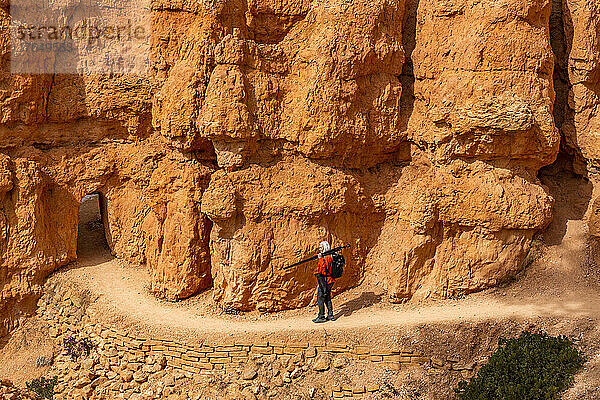 Vereinigte Staaten  Utah  Bryce-Canyon-Nationalpark  Seniorin mit Rucksack und Stativ beim Wandern im Bryce-Canyon-Nationalpark