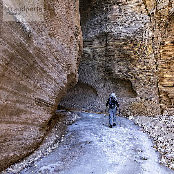 Vereinigte Staaten  Utah  Escalante  Rückansicht einer älteren Wanderin  die im Winter den Slot Canyon im Grand Staircase Escalante National Monument erkundet