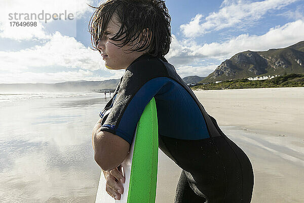Südafrika  Hermanus  Junge (8-9) ruht auf seinem Surfbrett