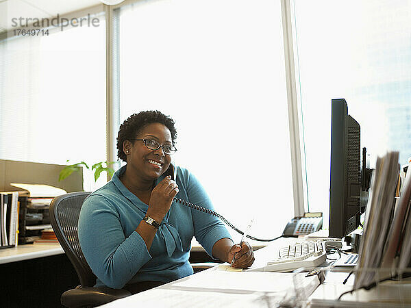 Geschäftsfrau sitzt am Schreibtisch und telefoniert