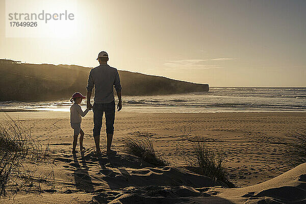 Vater und Tochter genießen den Sonnenuntergang am Strand