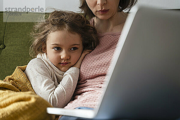Mutter mit kranker Tochter benutzt Laptop zu Hause