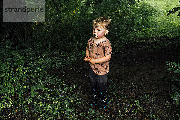 Boy wearing rubber boots standing in park