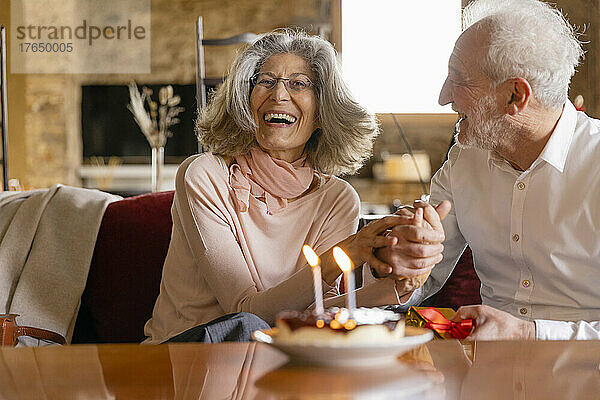 Glückliches älteres Paar mit Kuchen feiert Geburtstag im Boutique-Hotel