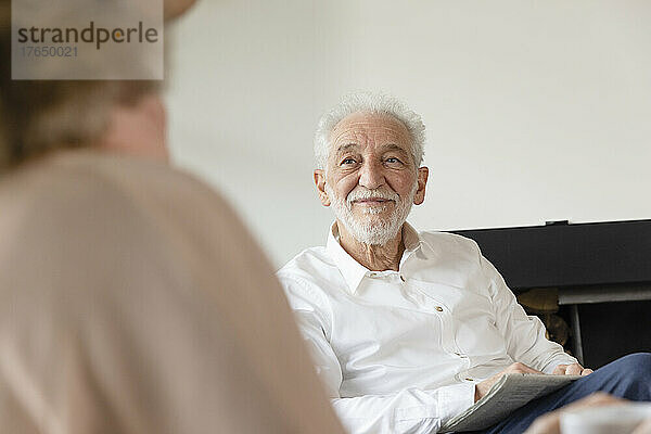 Lächelnder älterer Mann blickt Frau im Wohnzimmer an