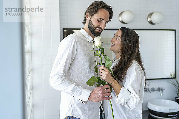 Couple holding white rose at home