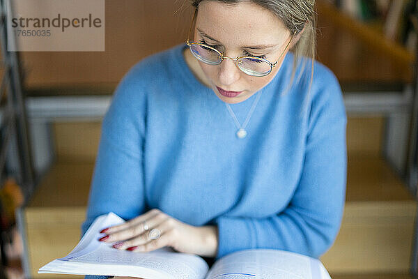 Junge Frau liest Buch auf der Treppe