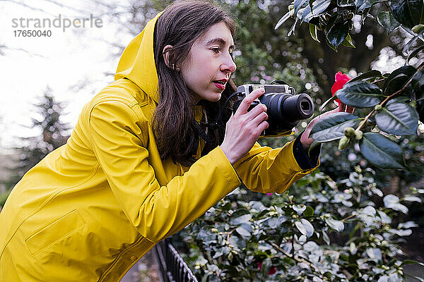 Junge Frau fotografiert Blumen mit der Kamera im Wald