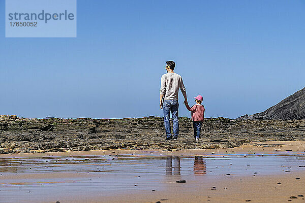 Vater und Tochter stehen auf einem Felsen am Strand