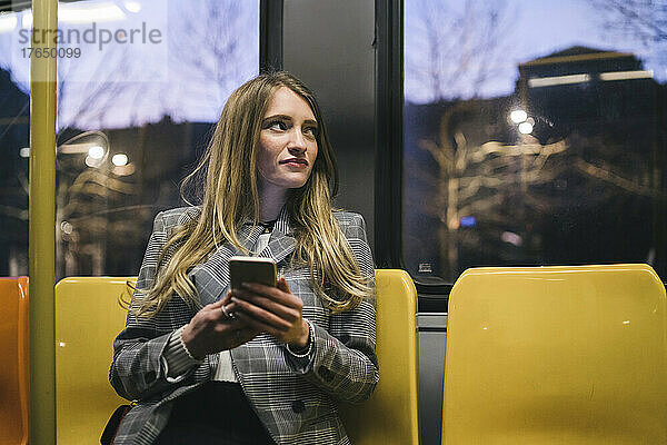 Frau hält Smartphone in der Straßenbahn