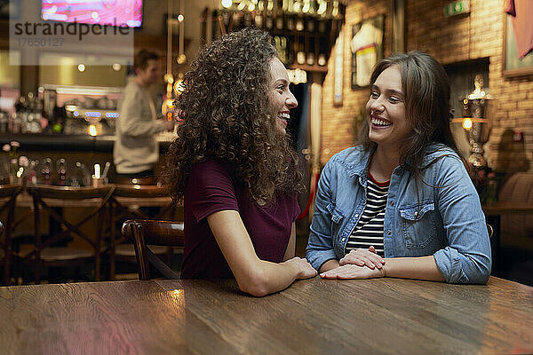 Two female friends talking in a pub