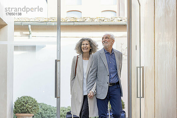 Glückliches älteres Paar hält Händchen bei der Ankunft im Boutique-Hotel