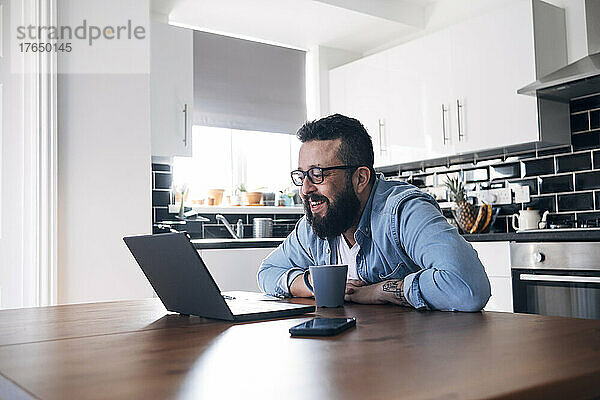 Lächelnder Freiberufler mit Laptop  der zu Hause arbeitet