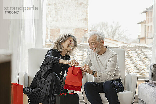 Lächelndes älteres Paar mit Einkaufstüten sitzt im Boutique-Hotel
