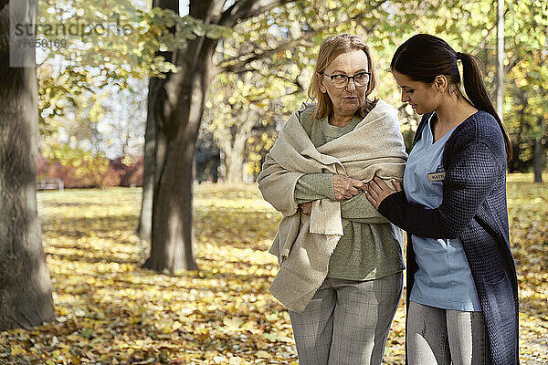 Ältere Frau spricht mit Krankenschwester beim Spaziergang im öffentlichen Park