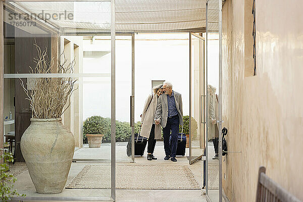 Älteres Paar mit Koffern geht im Boutique-Hotel spazieren