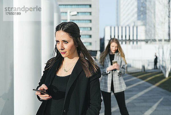 Junge Frau hält Smartphone vor einem Freund