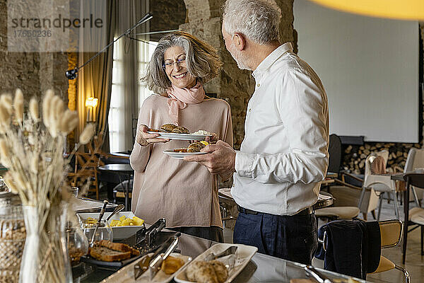 Glückliches älteres Paar genießt das Frühstück am Buffet im Boutique-Hotel