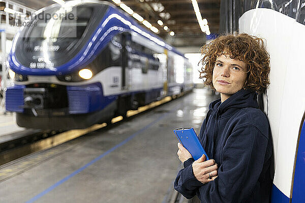 Ingenieur hält Aktenordner in der Hand und stützt sich auf Einschienenbahn in der Industrie