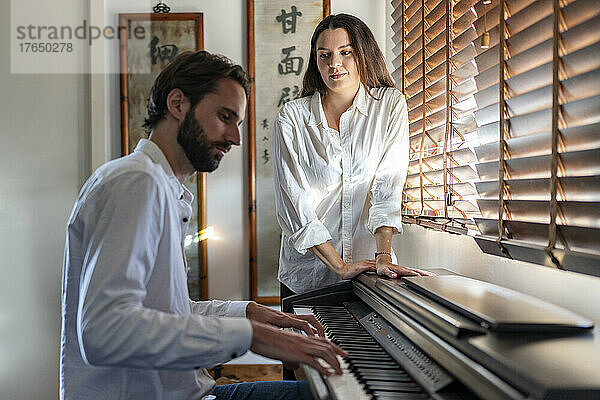 Frau hört Mann beim Klavierspielen zu