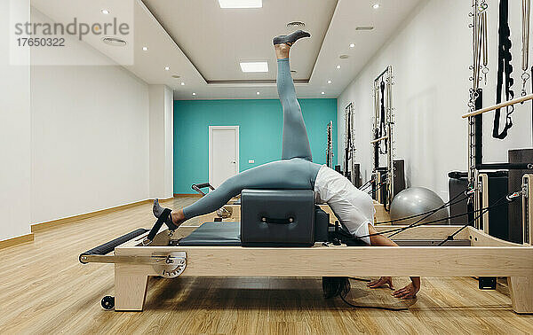 Flexible Frau trainiert im Studio auf einem Reformergerät