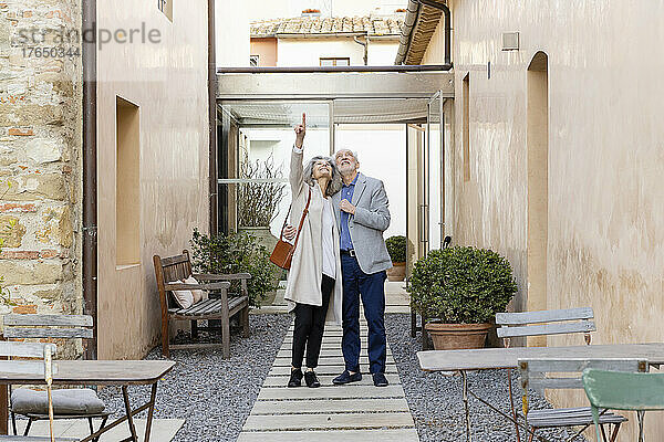 Ältere Frau und Mann stehen im Innenhof des Hotels und zeigen nach oben