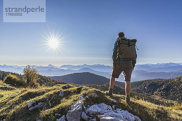 Männlicher Wanderer bewundert die Bayerischen Voralpen bei nebligem Sonnenaufgang