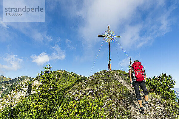 Frau mit Rucksack geht an sonnigem Tag durch Windkraftanlage