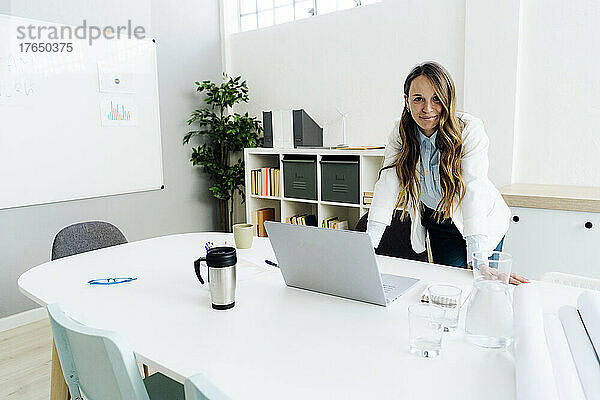 Lächelnde Geschäftsfrau mit Laptop am Schreibtisch