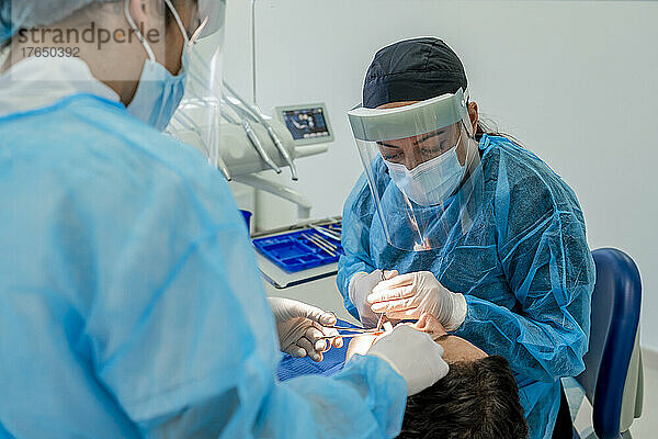 Surgeon with nurse doing surgery of patient in operating room at hospital