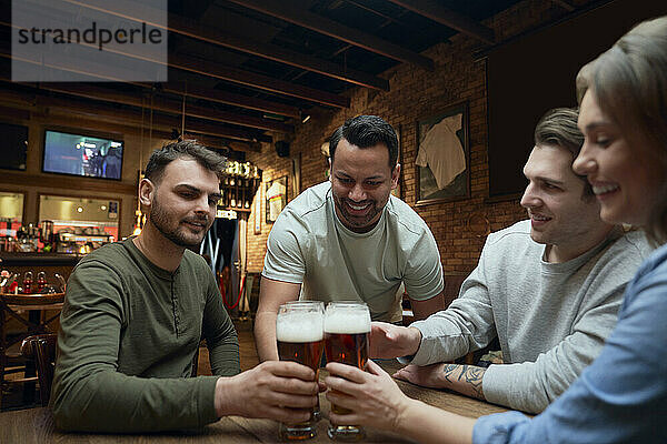 Friends meeting in a pub and clinking beer glasses