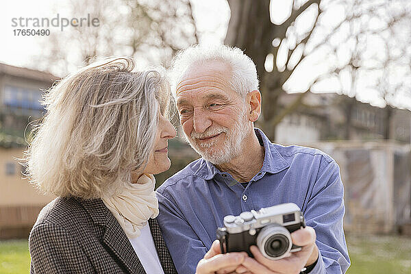 Glückliches älteres Paar  das sich an einem sonnigen Tag mit der Kamera anschaut