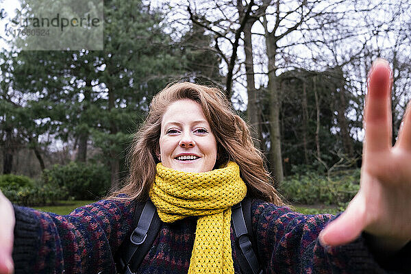 Glückliche junge Frau mit gelbem Schal genießt den Wald