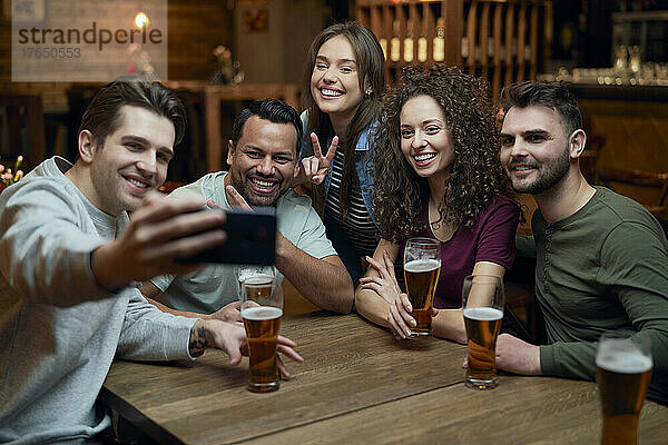 Gruppe glücklicher Freunde  die Bier trinken und ein Selfie in einer Kneipe machen