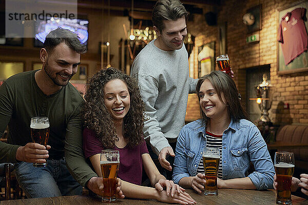 Smiling friends having beer in a pub