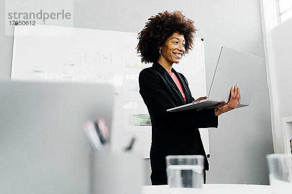 Glückliche Geschäftsfrau mit Laptop vor dem Whiteboard