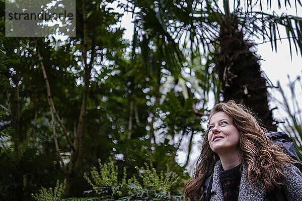Lächelnde junge Frau mit braunen Haaren im Wald