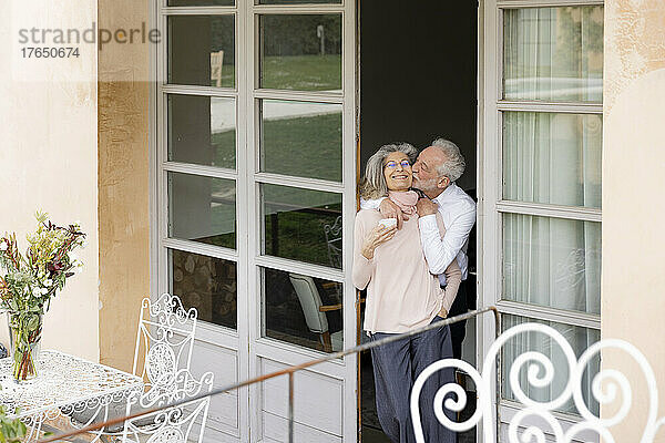 Romantischer älterer Mann küsst Frau  die an der Tür steht