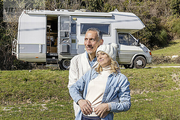 Älteres Paar umarmt sich im Urlaub vor seinem Wohnmobil