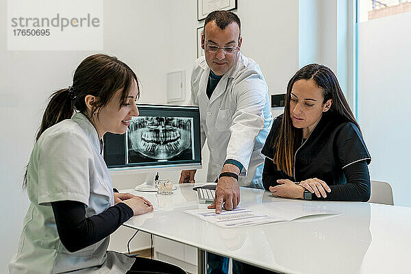 Zahnarzt bespricht medizinischen Bericht mit Krankenschwestern am Schreibtisch in der Klinik