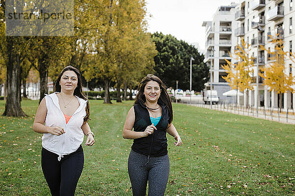 Glückliche Schwestern joggen im öffentlichen Park