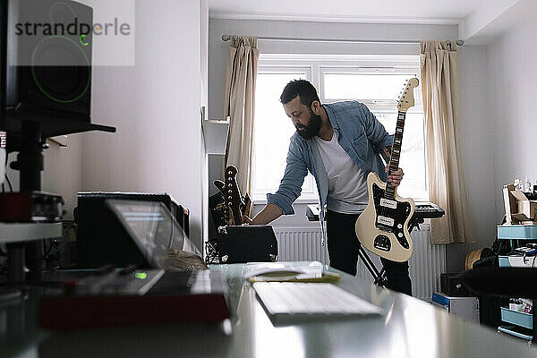 Freiberufler mit Gitarre und Verstärker im Heimstudio