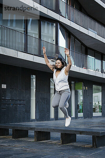 Frau springt vor Gebäudefassade