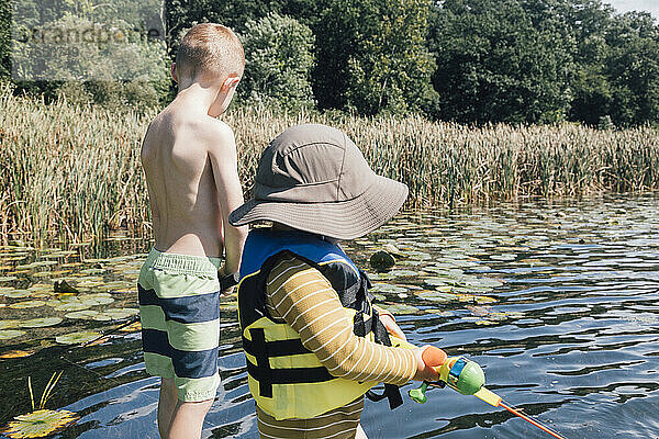 Brüder angeln an einem sonnigen Tag gemeinsam im Fluss