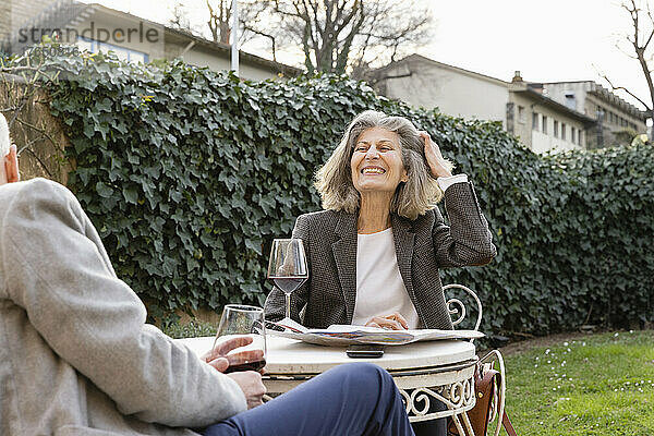 Glückliches Seniorenpaar mit Weingläsern sitzt im Hotelgarten