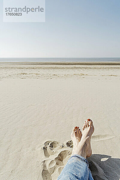 Frau sitzt an einem sonnigen Tag am Strand auf Sand