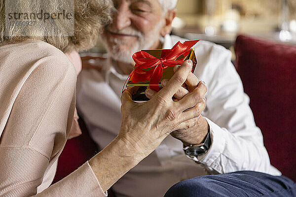 Älterer Mann und Frau halten Geschenk im Boutique-Hotel