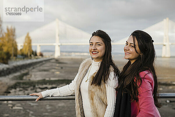 Glückliche Schwestern stehen am Geländer vor der Brücke